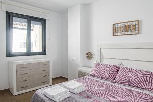 a white bedroom with a bed and a window at Nautilus 3 - Elegante Apartamento para 6 con Piscina, Wifi y AC en Rota in Rota