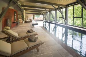 Habitación grande con piscina con sillas y ventanas. en Hôtel-Spa Le Saint Cirq, en Tour-de-Faure