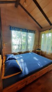 a large bed in a room with a window at Kempings Ezerpriedes in Burtnieki