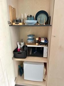 una cocina con una estantería con microondas y platos en Plaisances, les plaisirs du bord de Meuse - Chambre d'hôtes avec baignoire spa en Profondeville