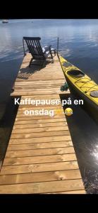 muelle de madera con banco y barco en el agua en Hideaway Engvej, en Guldborg