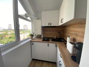 eine Küche mit weißen Schränken und einem großen Fenster in der Unterkunft Doinei Cozy Flat in Timişoara