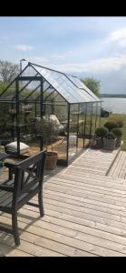 a glass pavilion with a bench on a wooden deck at Hideaway Engvej in Guldborg
