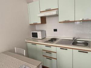 a kitchen with white cabinets and a sink and a microwave at La Terrazza del Centro in Bergamo