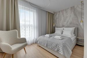 a bedroom with a bed and a chair and a window at Angielska Grobla 5 Apartinfo Apartments in Gdańsk