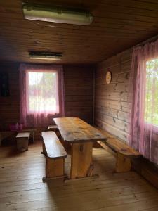 Habitación con mesa de madera y bancos en una cabaña en Česlovos sodyba, en Zarasai