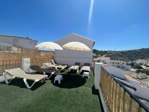 un patio con sillas y sombrillas en el balcón en La Posada, en Setenil