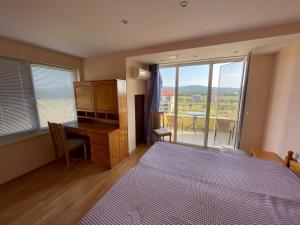 een slaapkamer met een bed, een bureau en een raam bij Laguna Sunset Appatments, sea and mountain view in Primorsko