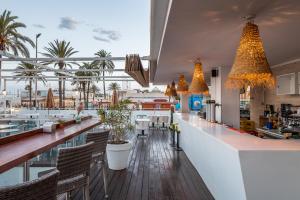 a restaurant with a bar with chairs and palm trees at Meraki Beach Hotel - Adults Only in Playa Pobla de Farnals