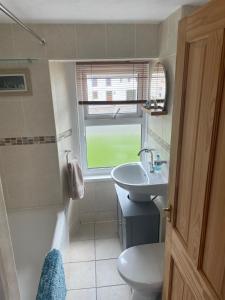 a bathroom with a sink and a toilet and a window at Cosy Seaside Cottage in Allonby