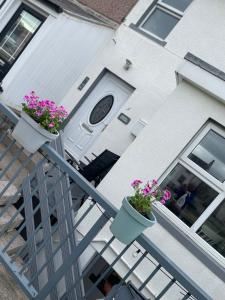 a house with two potted plants on a balcony at Cosy Seaside Cottage in Allonby