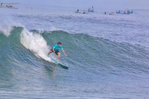 a man riding a wave on a surfboard in the ocean at Jungle House - surf & stay in Pulukan