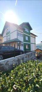 a house with a car parked in front of a bush at Apartments Amina Sarajevo in Sarajevo