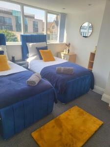 a bedroom with two beds and a blue couch at Perfect for Professionals & Business Travellers - Leeds City Views - Monthly Offers! in Leeds