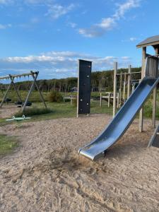 un parque infantil con un tobogán en la arena en Trevlig och havsnära stuga, en Glommen