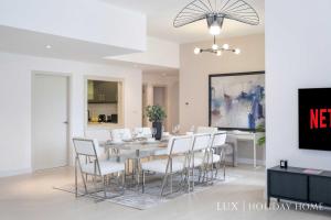 a dining room with a table and white chairs at LUX The Luxurious Central JBR Suite in Dubai