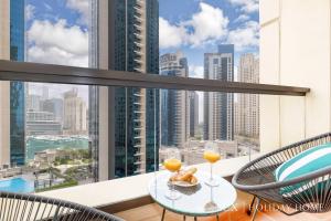 a balcony with a table and two glasses of orange juice at LUX The Luxurious Central JBR Suite in Dubai