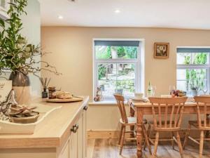 a kitchen with a table and chairs and two windows at Harefield Lodge in Pateley Bridge