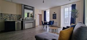 a living room with a couch and a kitchen with a table at Au pied de Sancerre logement Cosy in Saint-Satur
