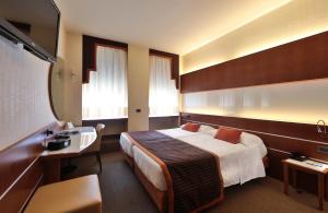 ミラノにあるベストウエスタン マディソン ホテルのベッドとデスクが備わるホテルルームです。