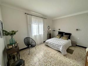 - une chambre avec un lit et une chaise dans l'établissement Appartement St Laurent, à Saint-Laurent-de-la-Salanque