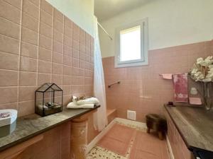 La salle de bains est pourvue de carrelage rose et d'une douche avec une fenêtre. dans l'établissement Appartement St Laurent, à Saint-Laurent-de-la-Salanque