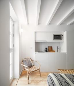 a white room with a chair and a kitchen at Loureiro 59 in Coimbra