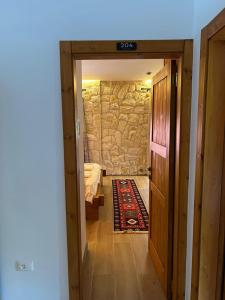 a door leading to a bedroom with a stone wall at Oda N'Bjeshke in Valbonë