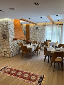 a restaurant with tables and chairs and a stone wall at Oda N'Bjeshke in Valbonë