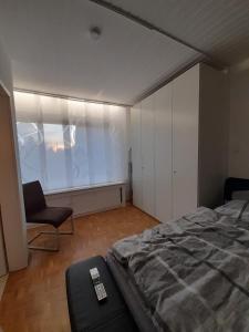 ein Schlafzimmer mit einem Bett, einem Stuhl und einem Fenster in der Unterkunft Willy und Gudrun in Rheda-Wiedenbrück