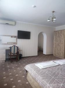 1 dormitorio con 1 cama, 1 silla y TV en Apart-hotel 24/7, en Kamianets-Podilskyi