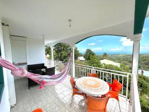 balcón con hamaca, mesa y sillas en Haut de villa calme avec jolie vue en Sainte-Rose