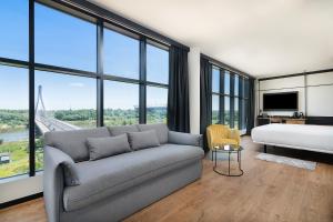 a living room with a couch and a bed and windows at Barceló Warsaw Powiśle in Warsaw