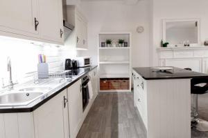 a kitchen with white cabinets and a black counter top at Chic Centrally Located 1 Bed Apt in Chester in Chester