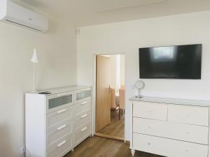 Dormitorio blanco con tocador y TV en la pared en Apartmány Mikulčice, en Mikulčice