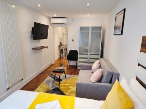 Camden Prime ApartHotel في لندن: غرفة معيشة مع أريكة وتلفزيون
