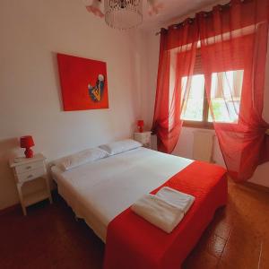 une chambre avec un grand lit avec des rideaux rouges dans l'établissement Sa Mama e Su Sole, à Alghero