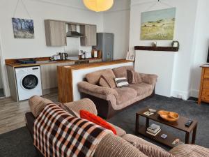 a living room with two couches and a kitchen at Gorgeous Sea View Apartment 5 mins To The Beach in St. Leonards