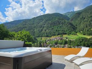 bañera de hidromasaje en el balcón con vistas a la montaña en Hotel Genzianella, en Commezzadura