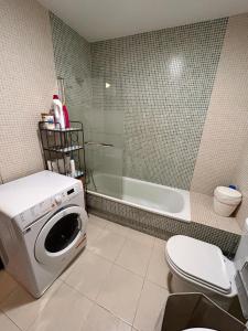 y baño con lavadora y bañera. en Apartamento Atico Algeciras en Algeciras
