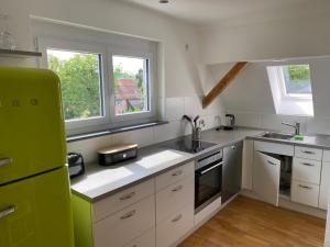uma cozinha com armários brancos e um frigorífico verde em Am Brunnen em Überlingen