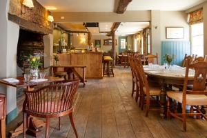 um restaurante com mesas e cadeiras de madeira e uma lareira em The Greyhound Inn em Wantage