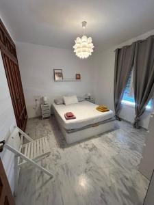 Habitación blanca con cama y lámpara de araña. en Apartamento Atico Algeciras en Algeciras
