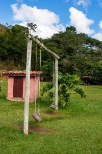 une balançoire vide installée dans une cour avec une maison dans l'établissement Recanto da roça, à Conservatória
