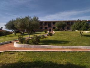 a building with a courtyard with trees in front of it at Residence Pinnetta Cala Bitta in Baja Sardinia