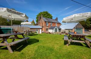 een groep picknicktafels met parasols in een tuin bij The Greyhound Inn in Wantage