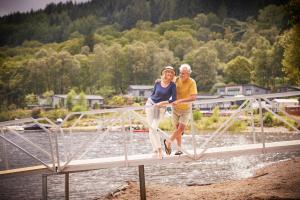 Ein Mann und eine Frau stehen auf einer Brücke in der Unterkunft Loch Lomond Holiday Park in Inversnaid