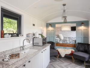 a kitchen with a sink and two chairs and a bed at Shepherds Stone in Holyhead