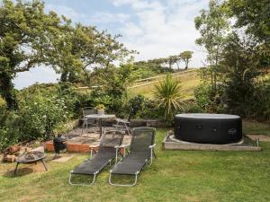 a backyard with a hot tub and chairs and a table at Shepherds Stone in Holyhead