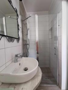 a white bathroom with a sink and a shower at Zsálya Vendégház in Csopak